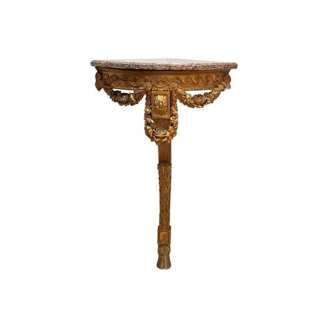 Wall-mounted corner console with a shaped pink and grey veined marble top above an apron carved in low relief with a...