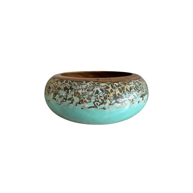 A hand-crafted mango wood bowl. The bowl was cut from a much larger slab of mango wood and features a hand painted...