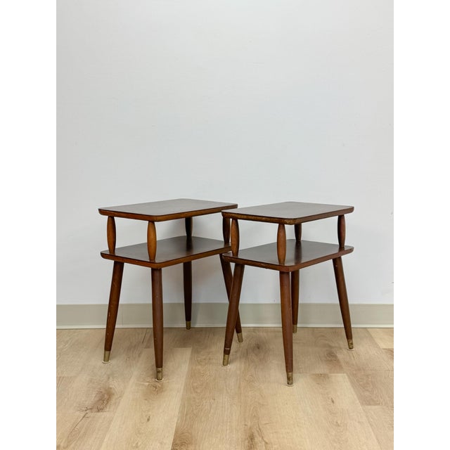 This fun and characterful pair of vintage MCM atomic two-tier end tables are a playful and practical mid-century modern...