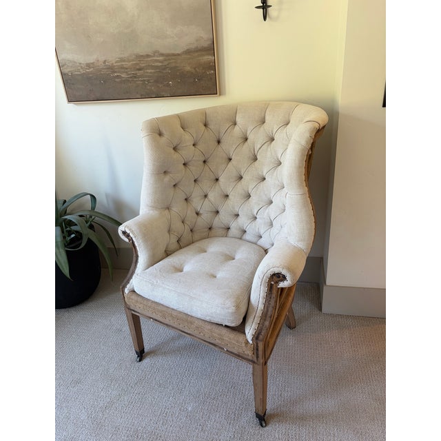 Mid 19th century, an S-scrolled wing back with tufted and tied-back upholstery, and two straight front legs on brass...