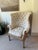 Mid 19th century, an S-scrolled wing back with tufted and tied-back upholstery, and two straight front legs on brass...