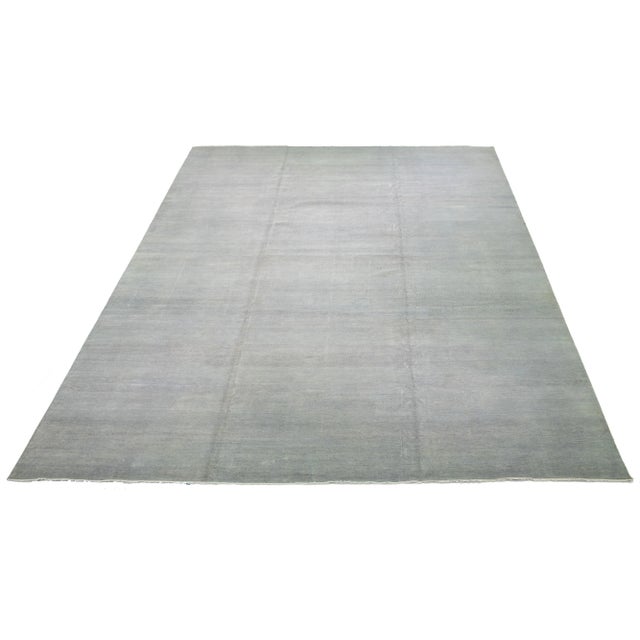 This elegant hand-knotted wool rug features a stunning contemporary design, showcasing a meticulously crafted gray field...