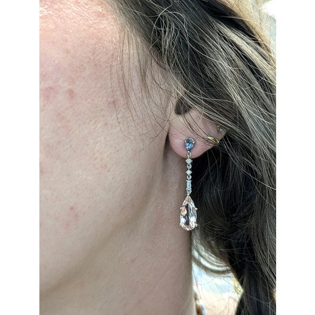 Elegant yet eye-catching, these 14K white gold earrings feature pear-shaped Morganite (3.42ct) and Aquamarine (0.76ct)...