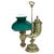 Late 19th-century student lamp with an ornate silvered-metal cornucopia-form body, a green glass shade, and a decorative...