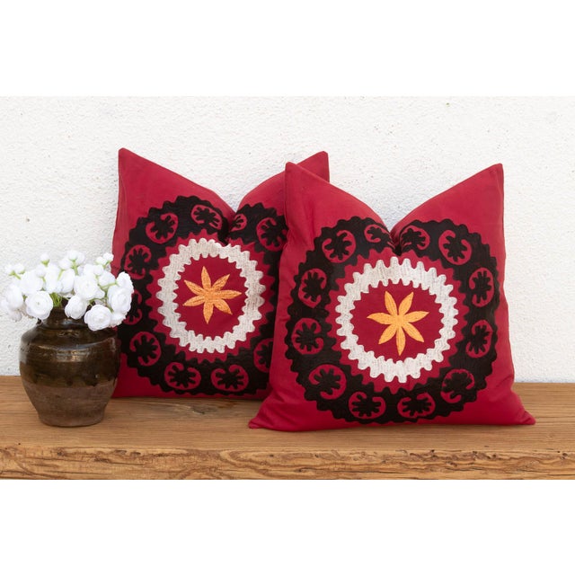 A bold black scalloped medallion anchors each pillow in this well-matched pair — a wine-red ground framing a cream ric-rac...
