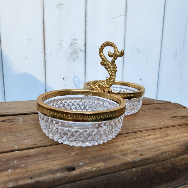 This vintage crystal and gold ormolu serving dish features double diamond-cut bowls, framed with intricate gilt detailing....