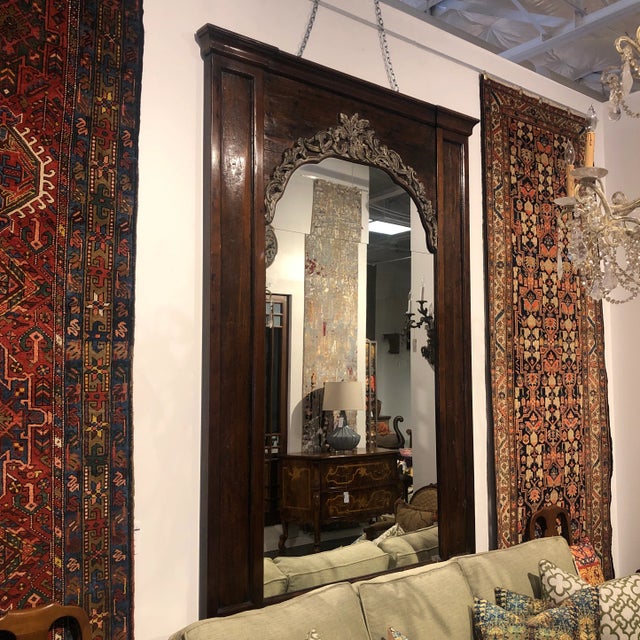 Hand-carved poplar and walnut tall statement mirror featuring an elegant floral cornice in an oxidized silver leaf finish....