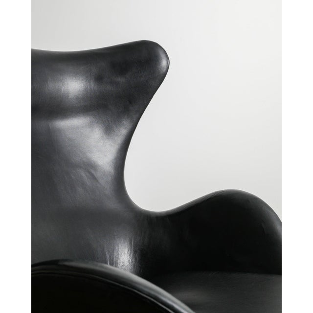 A very rare and beautiful example of an iconic danish mid century "3317 / egg" armchair in original black patinated...