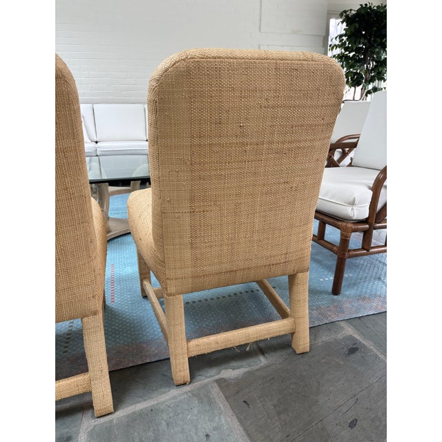 Unique pair of fully upholstered raffia side chairs. The chairs feature natural woven raffia upholstery with rich textural...
