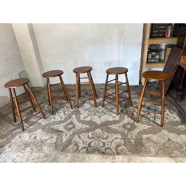 Vintage early american shaker style oak wood round seat bar stools. It features turned legs and stretchers, and a round...