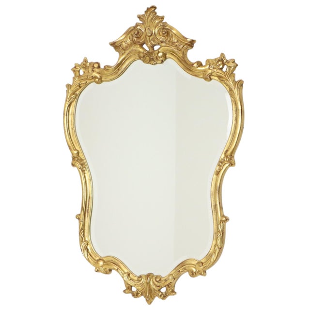 Large gold-leaf gilded Deknudt mirror featuring beveled glass; the frame is made of composite wood. This is a classic...