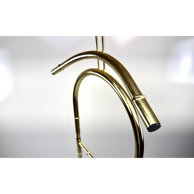 A stylish mid-century Hollywood Regency valet stand featuring a polished brass-finished metal frame with an elegant faux...