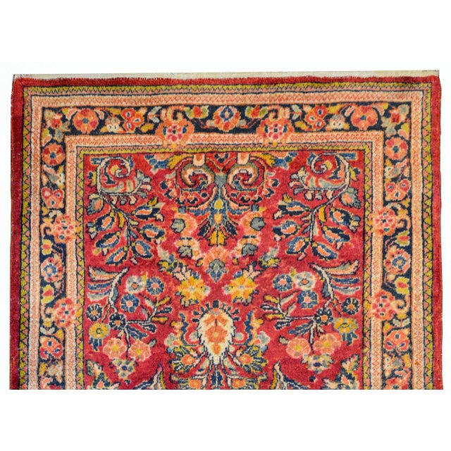 Beautiful early 20th century Persian Sarouk runner with an all-over mirrored floral pattern woven in cranberry, gold, pale...