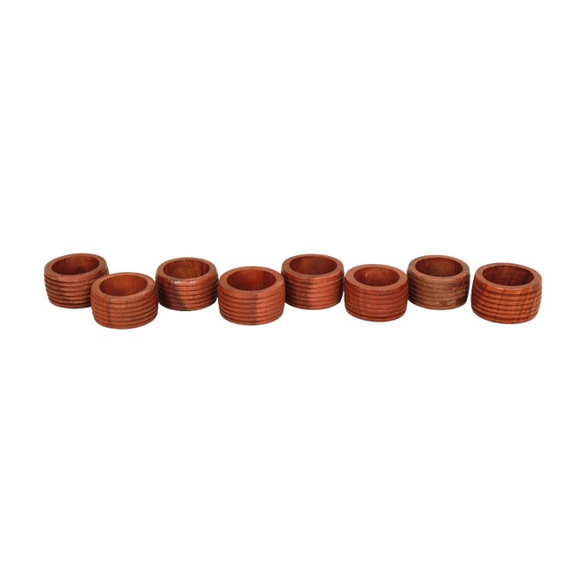 A set of eight napkin rings, made of teak. Richly grained wood is carved in a gentle barrel shape, finished with six...