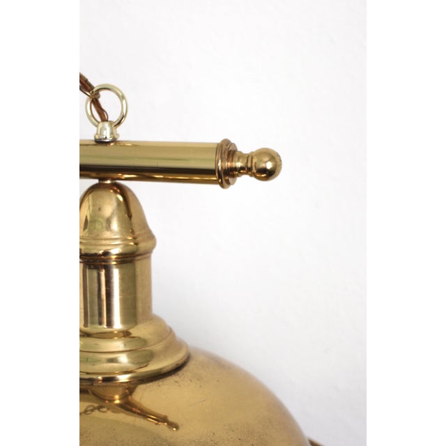 A large brass and white light fixture that hangs from chains from a central fixture. White enamel interior to large...