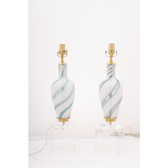 A beautiful pair of Murano glass table lamps with predominantly white and light blue swirls with subtle gold accents....