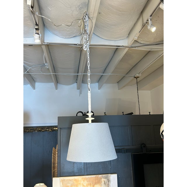 Sculptural pendant featuring a metal shade finished in textured white plaster, offering a refined balance of softness and...