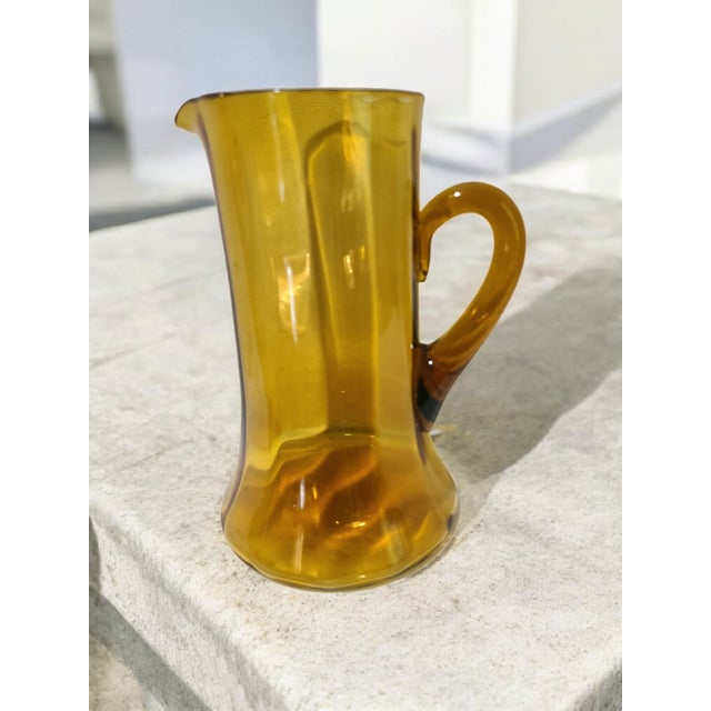 Crafted with meticulous care, this Vintage Italian Hand Blown Amber Art Glass Pitcher is a testament to the timeless...