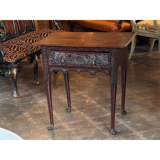 An English side table of lowboy proportions, the long frieze drawer centered by a fluted shell within richly scrolling...