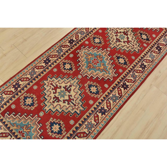 A tribal Caucasian Kazak runner hand-knotted with fine wool on a cotton foundation. This rug features a row of geometric...