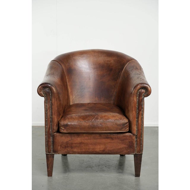 This sturdy vintage sheepskin club armchair features a rich patina and an authentic vintage appearance, and is finished...