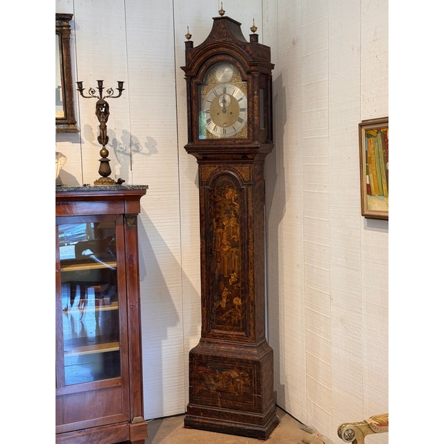 A George III tall case clock with a dark ground chinoiserie-decorated case — figures, pagodas, and flowering trees in gold...
