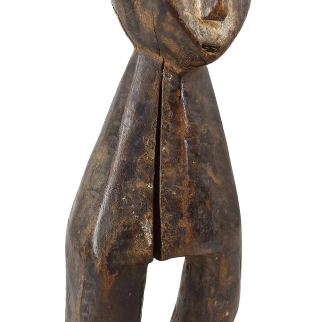 The Lega Warega Miniature Figure from Congo is a standing sculpture with a stylized body, showing signs of age and use....