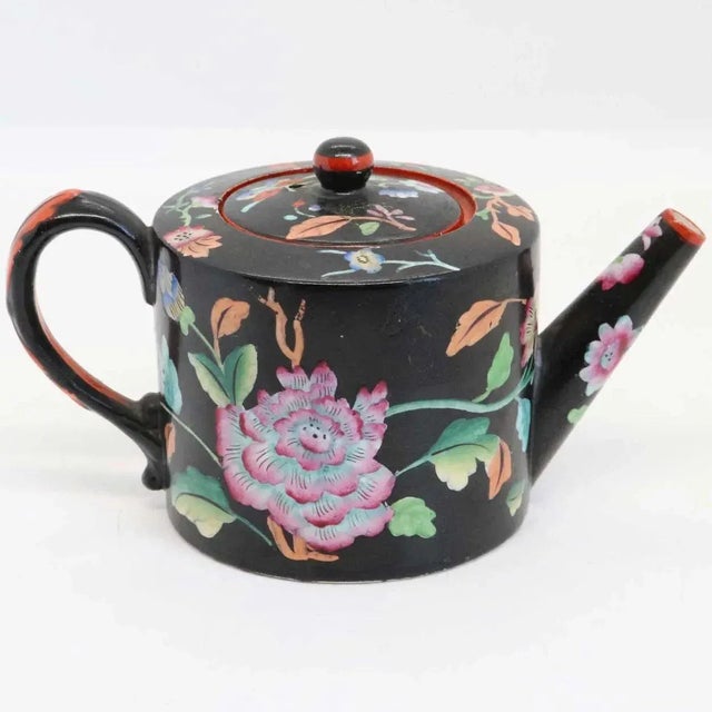 A rare, miniature, antique Davenport one-cup teapot of barrel shape with multi-color flowers on a matte black ground with...