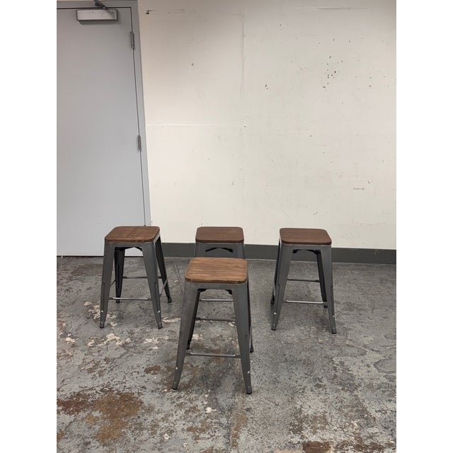 Design Plus Gallery presents a Set of Four Industrial Style Counter Stools. Each stool pairs a squared shaped wood seat...