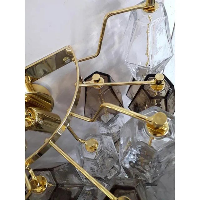 Contemporary scenographic set of two wall sconces in Murano glass. Transparent end fumè "Poliedri" in a gold24k bath of...