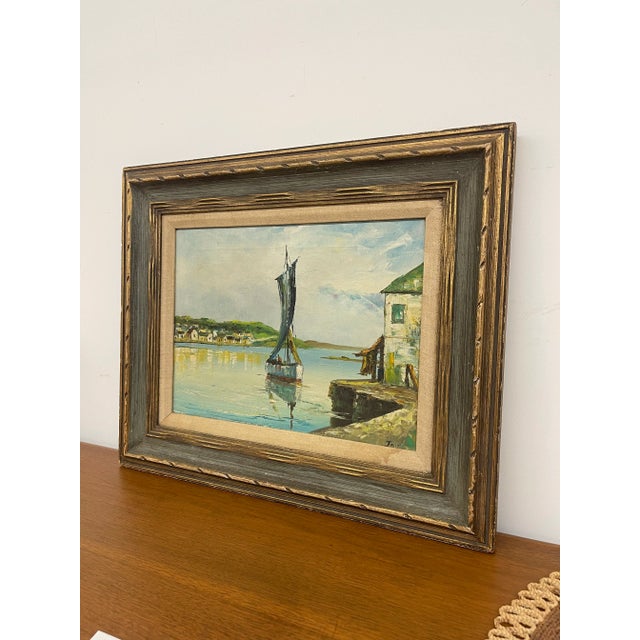 A charming vintage mid century painting depicting a serene coastal harbor scene, signed "Jay" in the lower right corner....