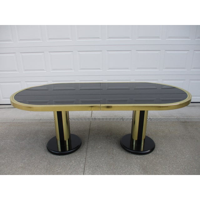An oval Design Institute of America (DIA) smoked glass and brass chrome finish dining table. This table sits atop two...