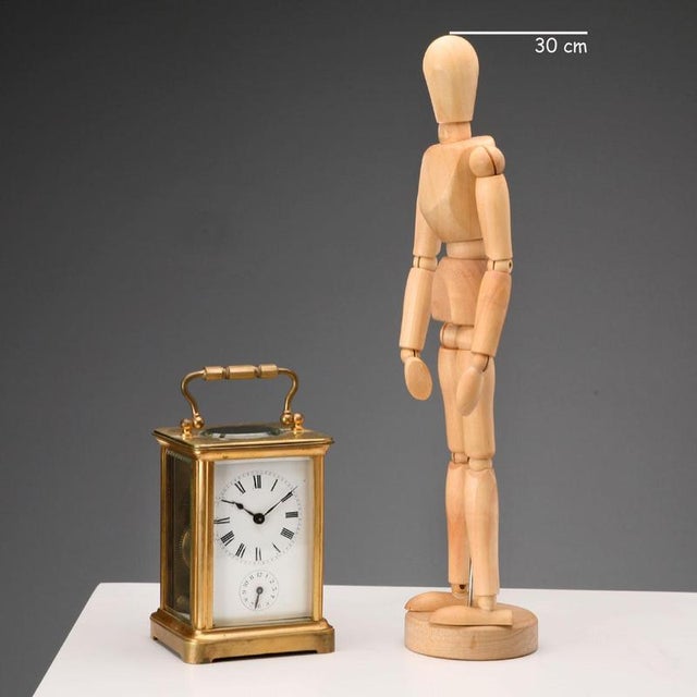 Travel clock in gilt bronze and beveled glass. Visible movement and mechanism. Enamelled metal dial with Roman numeral...