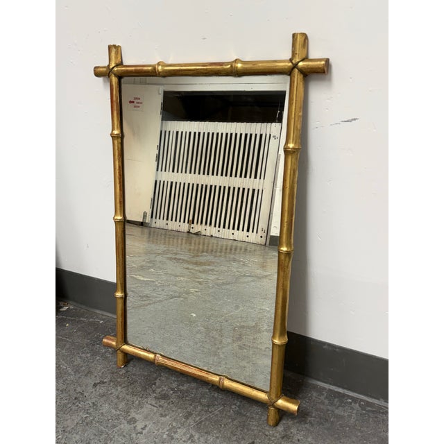 Design Plus Gallery presents a Vintage Giltwood Faux Bamboo Wall Mirror. The rectangular mirror is framed by carved wood...