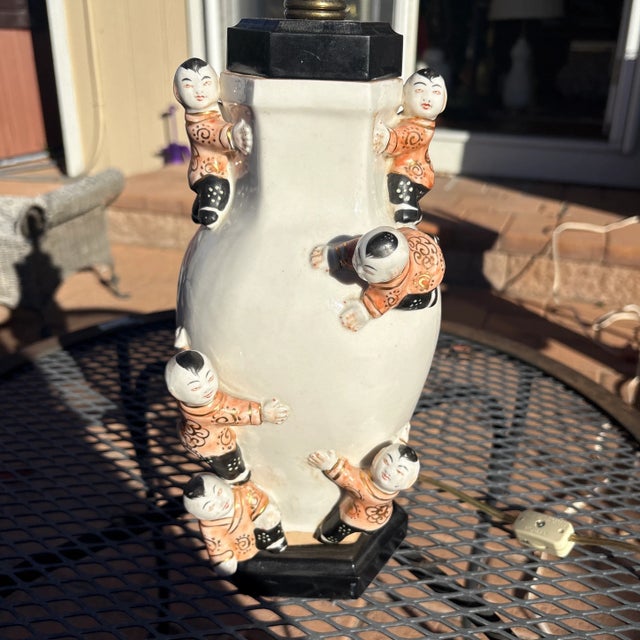 Vintage Chinoiserie Climbing Children Lamp that has white porcelain with boys wearing coral silk jackets and black pants...