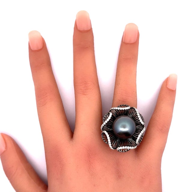 A striking tahitian pearl, measuring 15.5mm, is the centerpiece of this contemporary ring. The pearl's deep and lustrous...