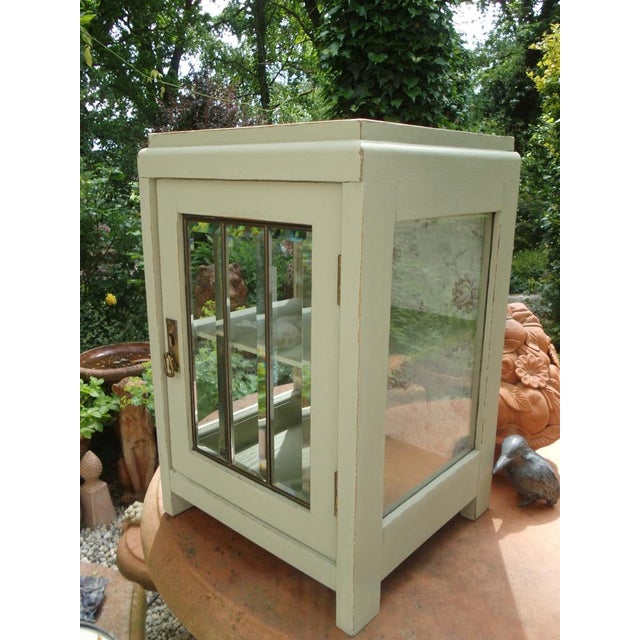 An antique, small wooden box with an unusual door, whose faceted glass panes are individually set in brass. The glass...