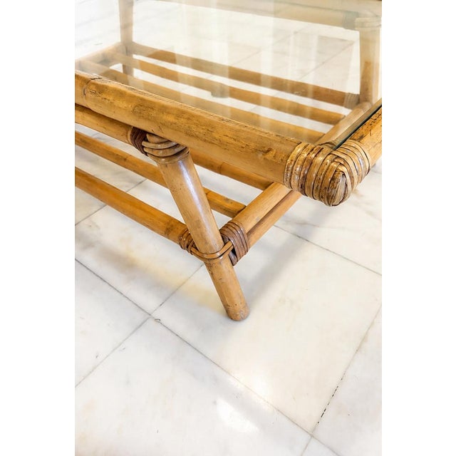 Glass-top rattan coffee table in the style of Paul Frankl. The item is unmarked. The table features a glass top in a...