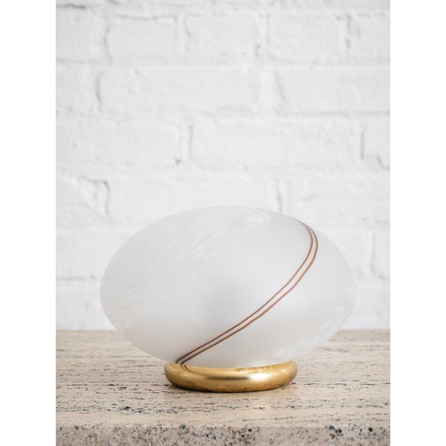 Petite globe table lamps in swirl patterned Murano glass with brass bases. Sourced in Italy.