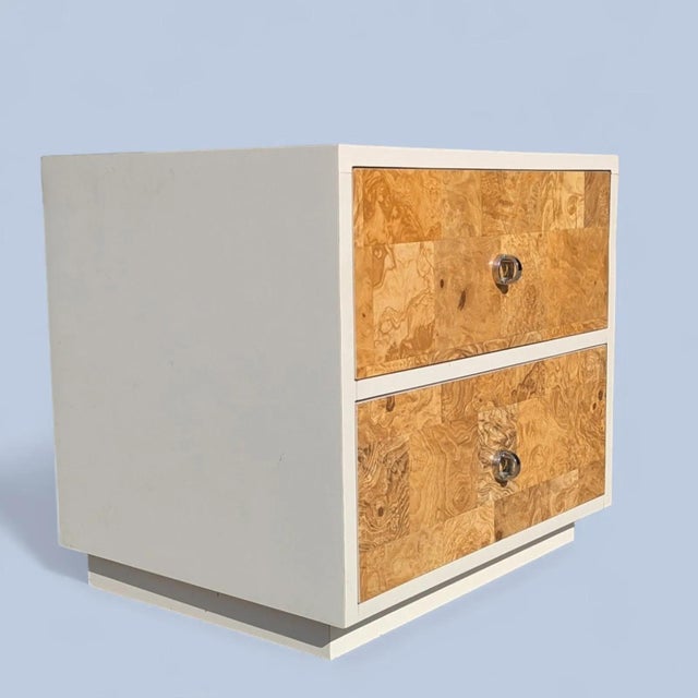 A compact vintage nightstand from the 1970s featuring a faux-burl laminate finish and streamlined chrome pulls. The...
