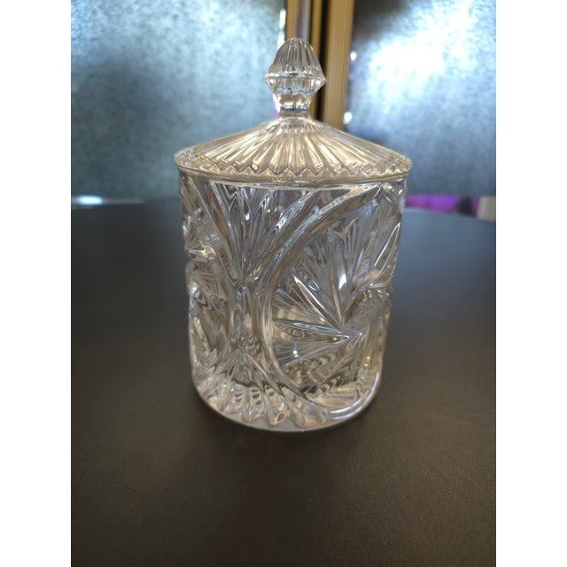 Small sized crystal canister featuring swirling and floral like patterns, there is a six sided star design in the middle...