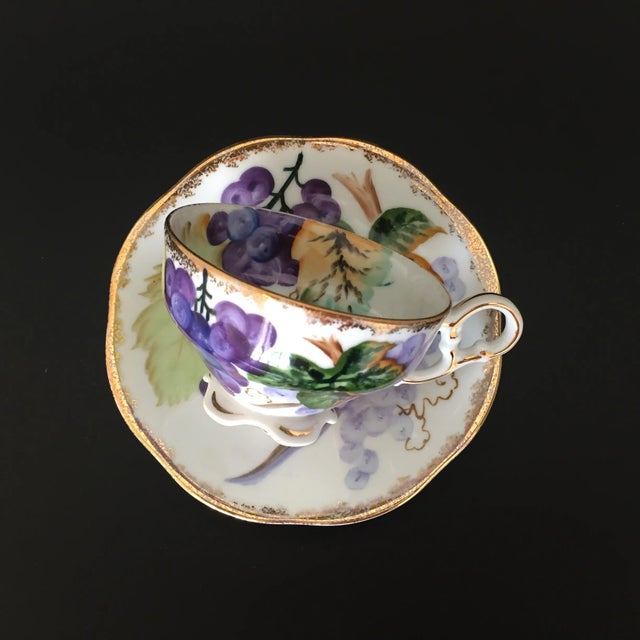 A Mid-Century Norcrest NW-C5A porcelain footed tea cup and saucer set, beautifully adorned with hand-painted grape bunch...