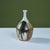 Hand thrown stoneware bud vase features a small spout opening and varying colors of drip gaze throughout the form in...
