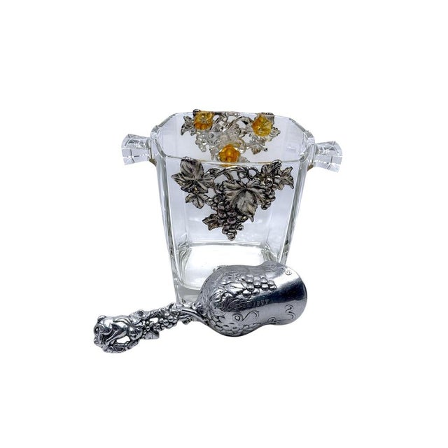 Elegant glass ice bucket featuring grape accents, paired with a matching ornate scoop, ideal for entertaining or...