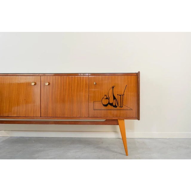 Italian sideboard of the 50s made of Sapellly wood in its color and polychrome in black. Black glass lid, four drawers in...