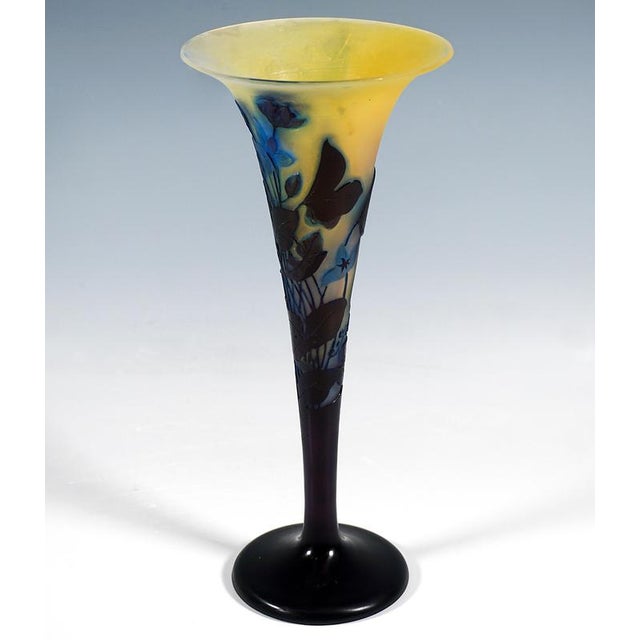 Trumpet-shaped vase with a wide flared rim resting on a stepped round foot; colourless glass with milky white and yellow...