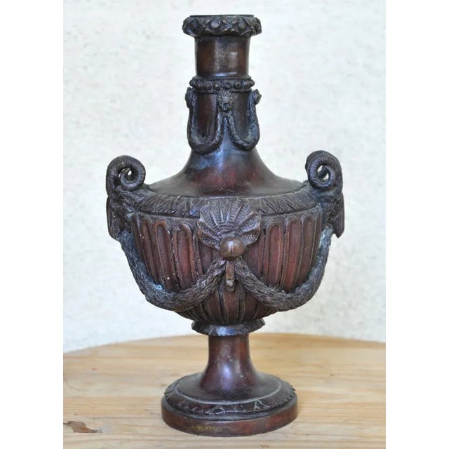 The side of this unique vase has relief features depicting garlands. It is about 11.5" high, 6.5" wide, 6" deep and weigh...