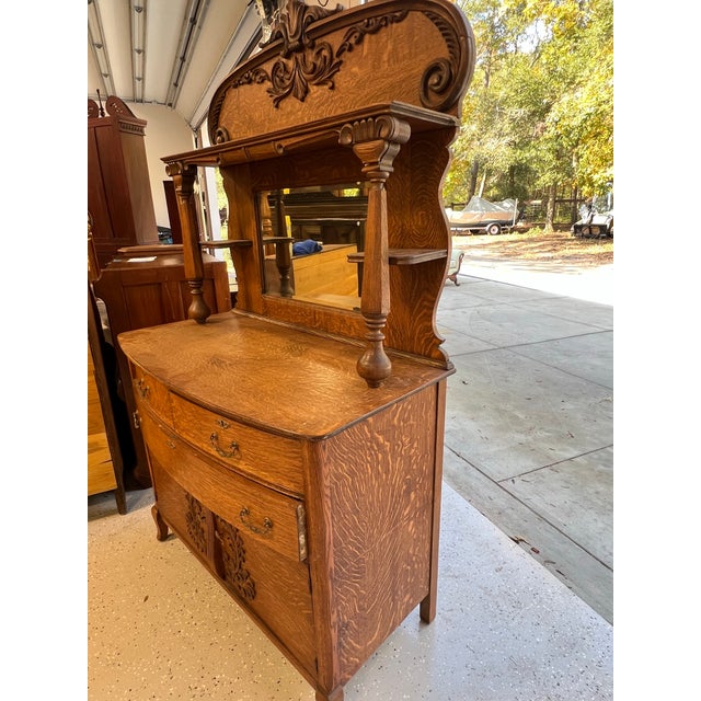 This sideboard represents the American Victorian furniture tradition of the late 19th to early 20th century, when quarter-...