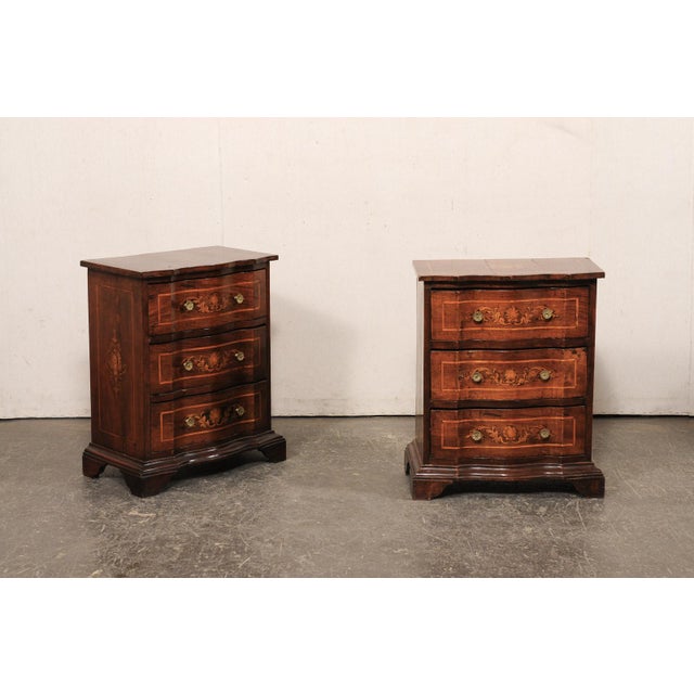 An Italian pair of small serpentine side chests, with decorative inlay, veneers, and banding, from the 19th century. These...