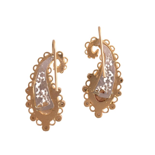 A pair of dangle earrings crafted from 18k yellow gold and sterling silver. The design features a paisley shape with...